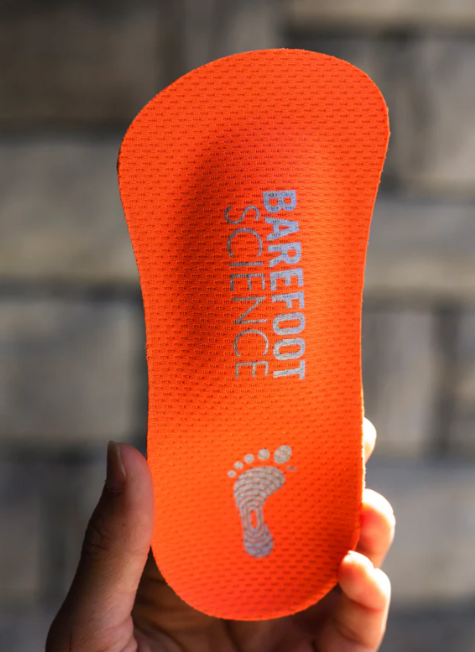 Bright orange 3/4 length insole with textured surface, "Barefoot Science" text and footprint logo in white.