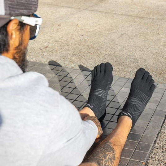 Black toe socks with individual compartments, low-cut no show design, textured breathable fabric on feet.