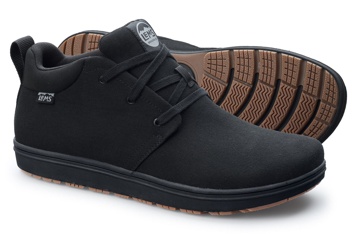 Black canvas Lems Chukka Grip casual shoes with black laces and brown textured rubber soles.