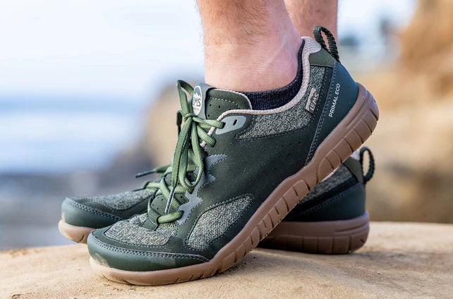 Green Lems Primal Eco athletic shoes with brown soles and knitted upper on feet outdoors.