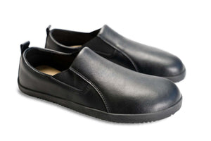 Black vegan leather slip-on sneakers with elastic side panels and textured rubber soles.
