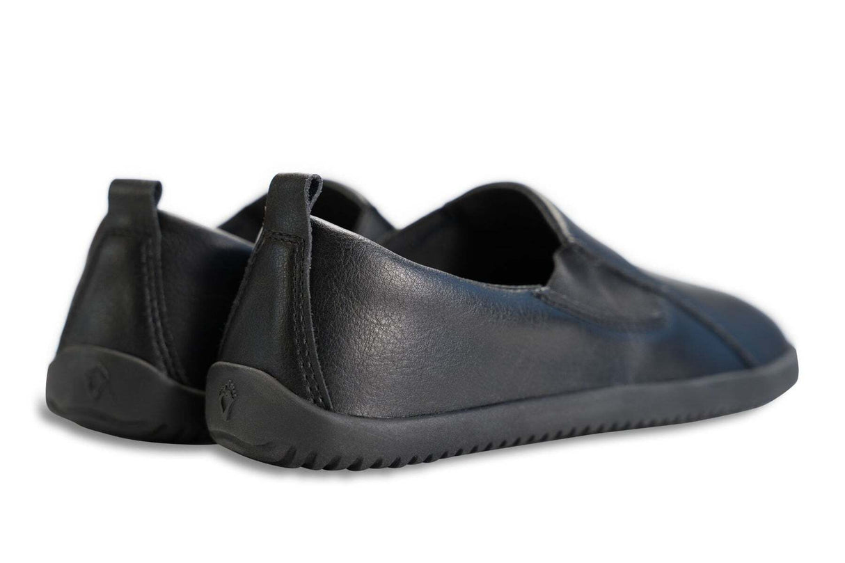 Black vegan leather slip-on sneakers with textured soles and low-profile heel tabs.
