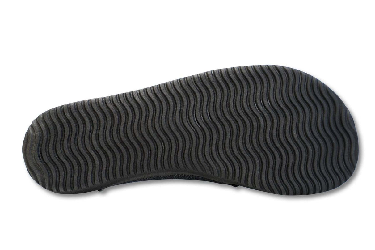 Black sneaker sole with wavy tread pattern in vegan leather slip-on style.