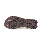 Brown rugged sole of a trail running shoe with deep multi-directional lugs for traction.