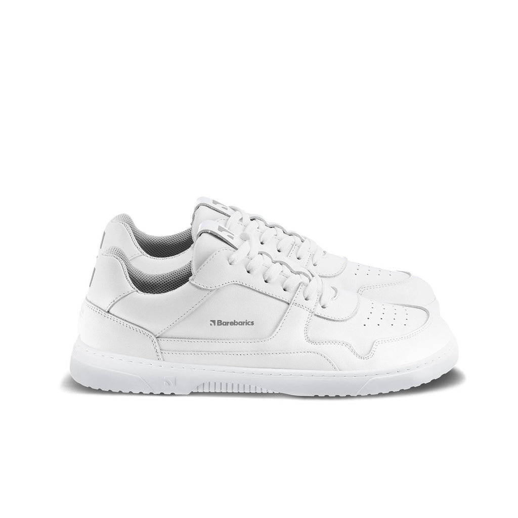 All-white leather low-top sneakers with textured sole and perforated toe detail.