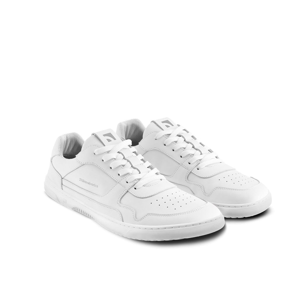 All-white low-top leather sneakers with perforated toe and lace-up design.