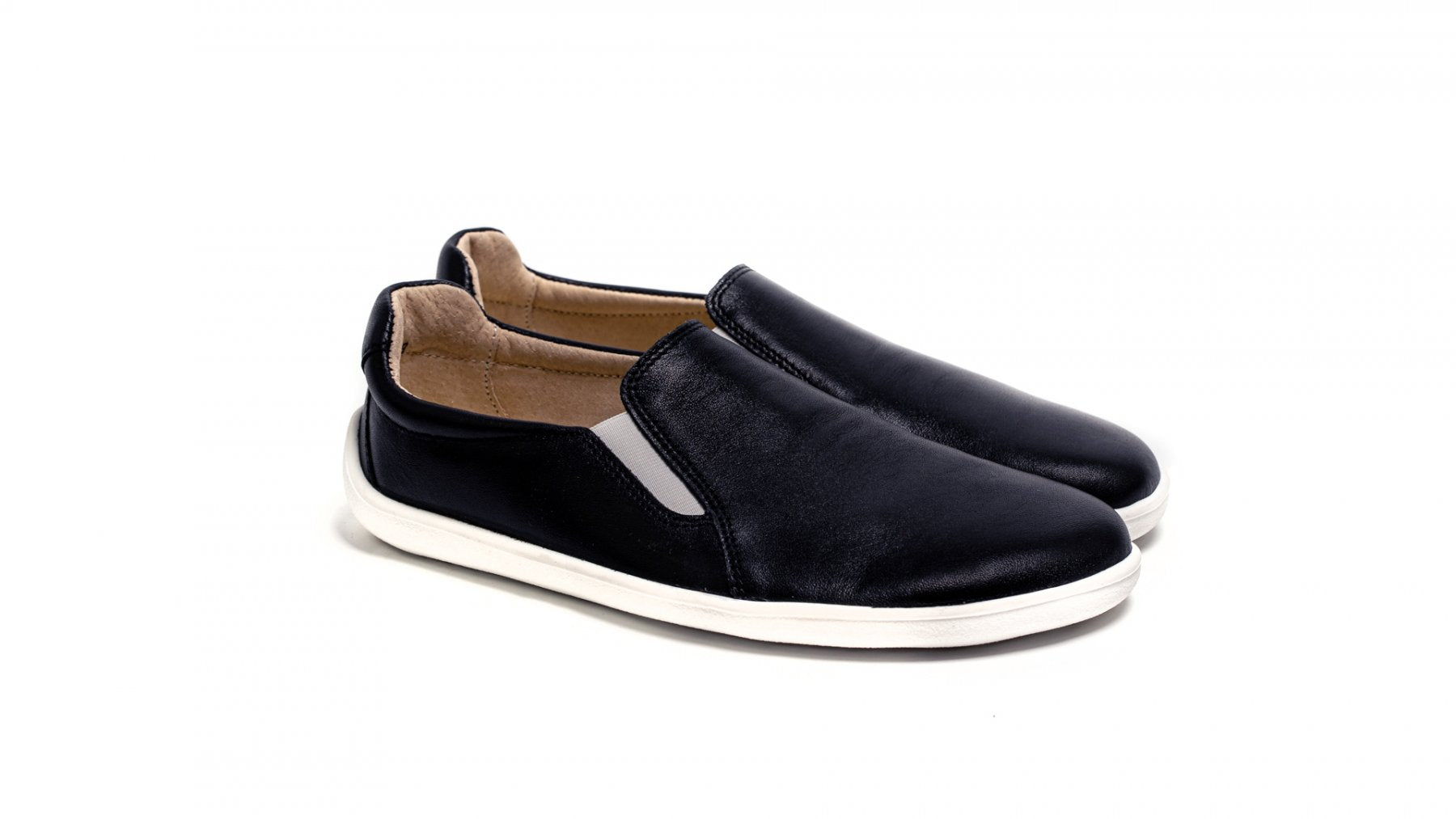 Black slip-on casual shoes with white soles and tan interior lining.