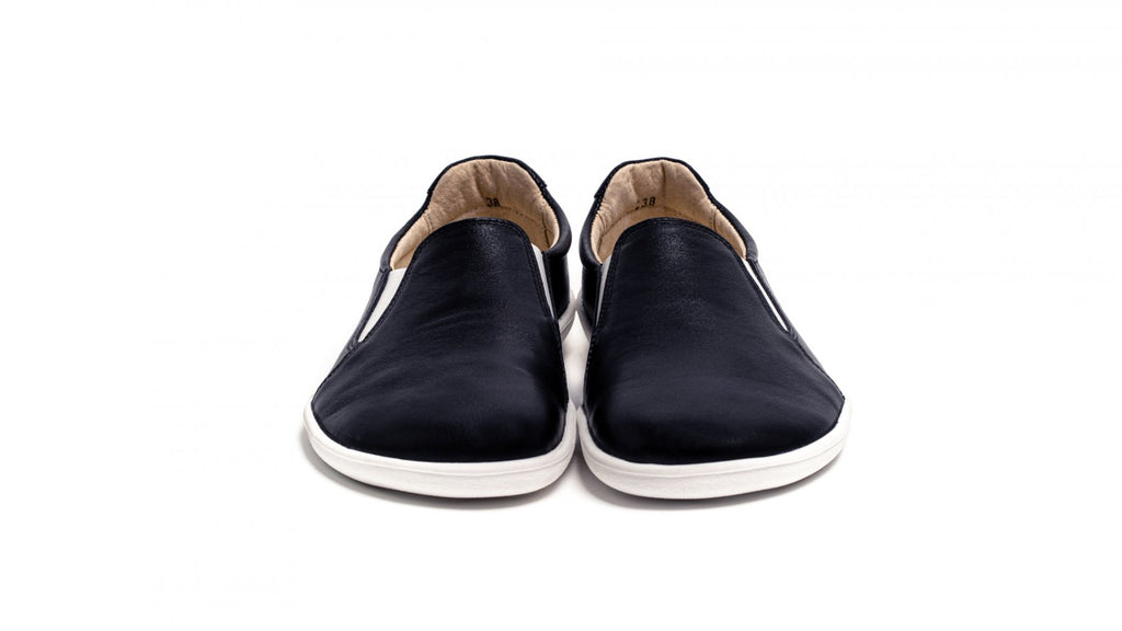 Black slip-on casual shoes with white soles and rounded toes, smooth leather upper.