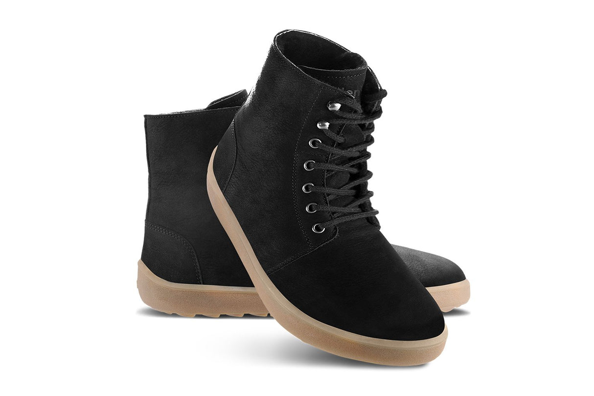 Matt black lace-up winter boots with tan rubber soles and metal eyelets.