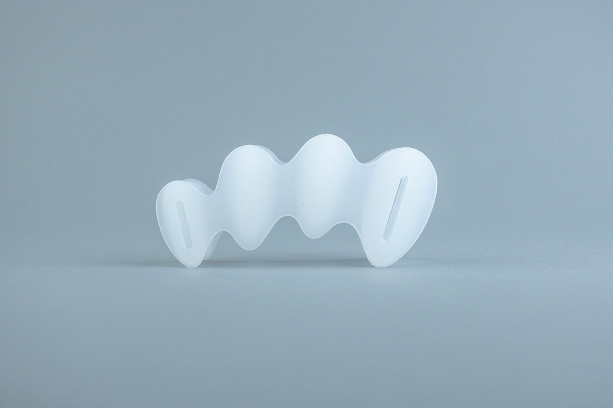 Clear flexible silicone toe spacer with five individual loops for each toe on light gray background.