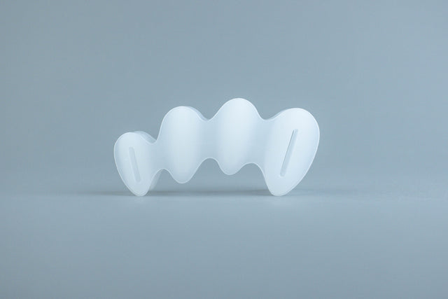 Clear flexible silicone toe spacer with five individual loops for each toe on light gray background.