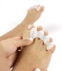 White silicone toe spacer on a foot, separating and aligning toes for comfort and correction.