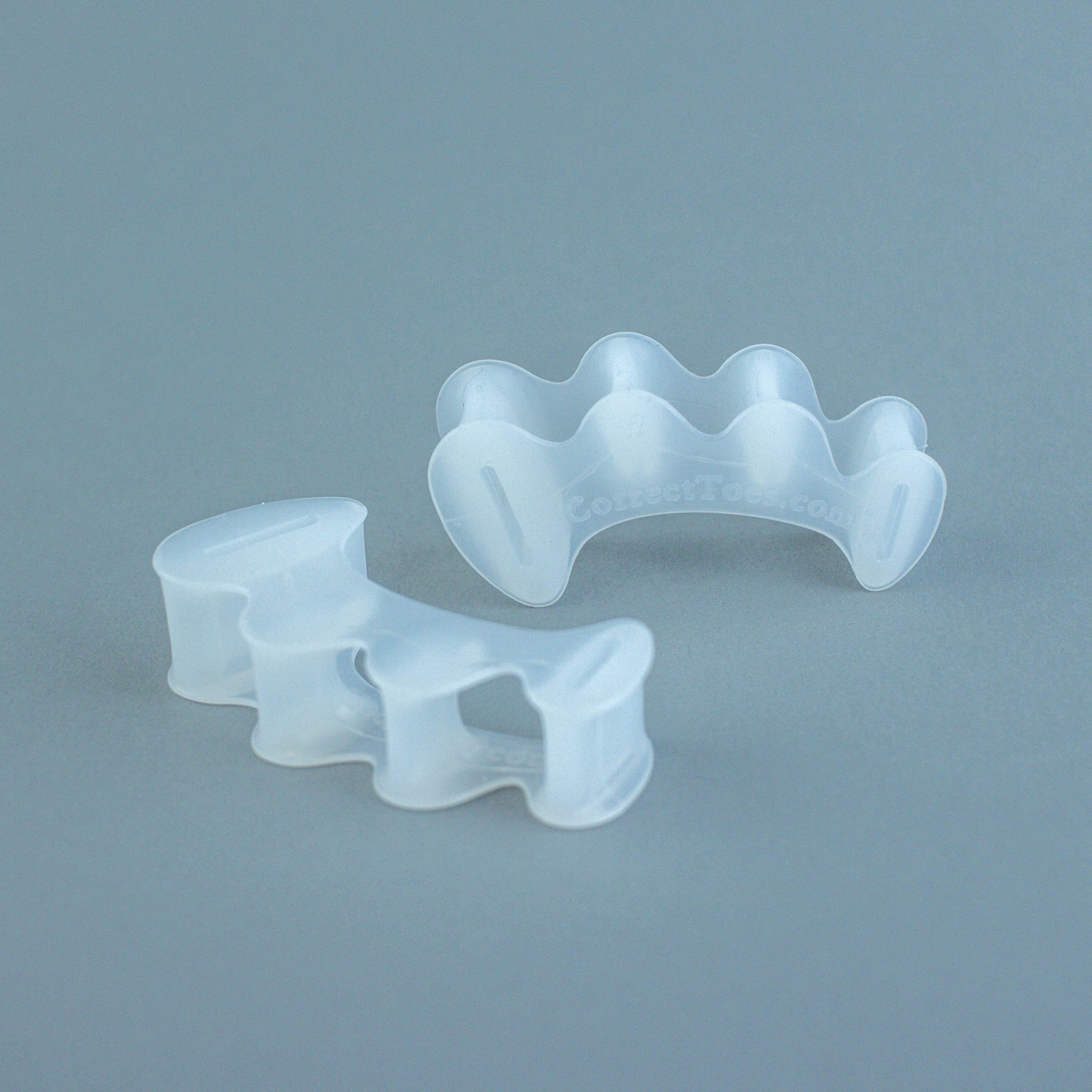 Clear silicone toe spacers with wave-like design, shaped to separate toes comfortably.