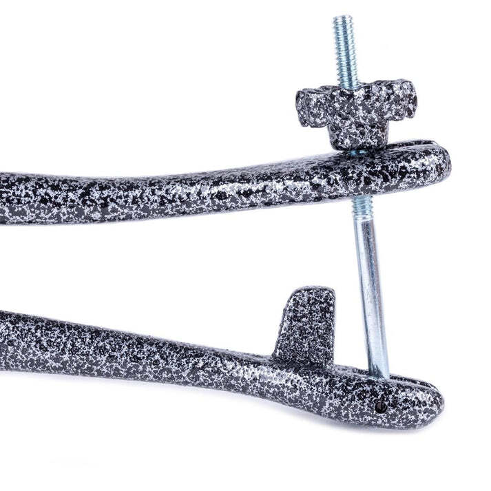 Close-up of textured black cast iron bunion stretcher with adjustable screw and wingnut mechanism.