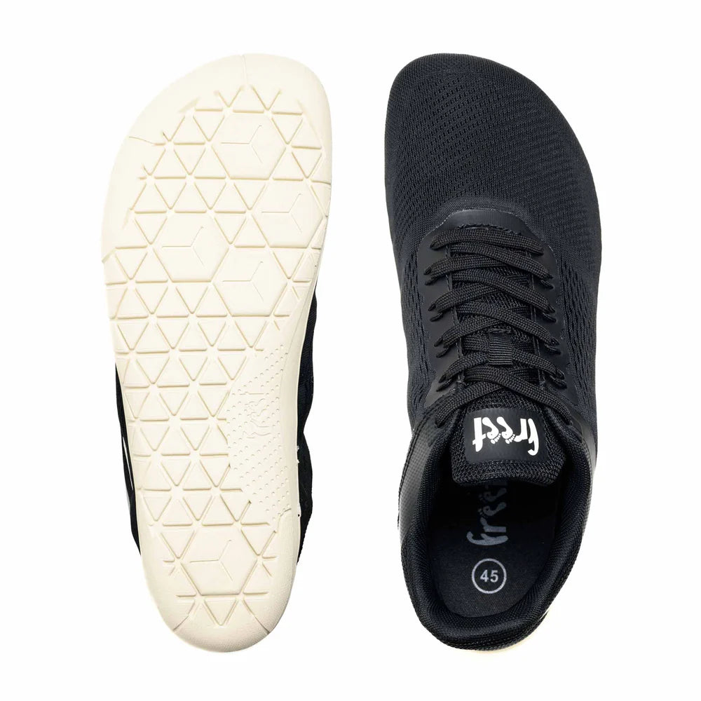 Black minimalist sneaker with breathable mesh upper, white geometric-patterned sole, and lace-up closure.