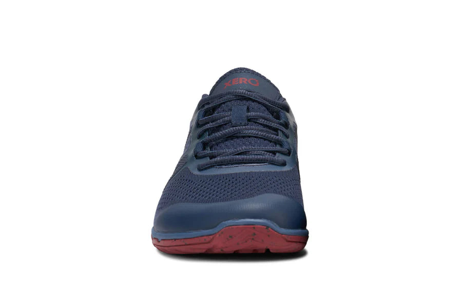 Blue athletic shoe with red sole on a white background
