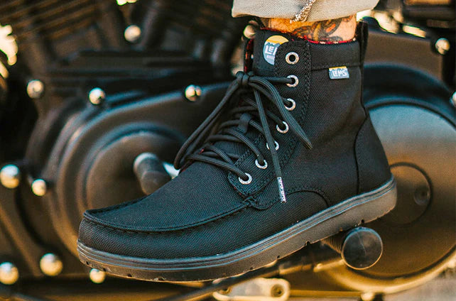 Black nylon Lems Boulder Boot Vegan with high ankle collar and black laces on motorcycle footrest.