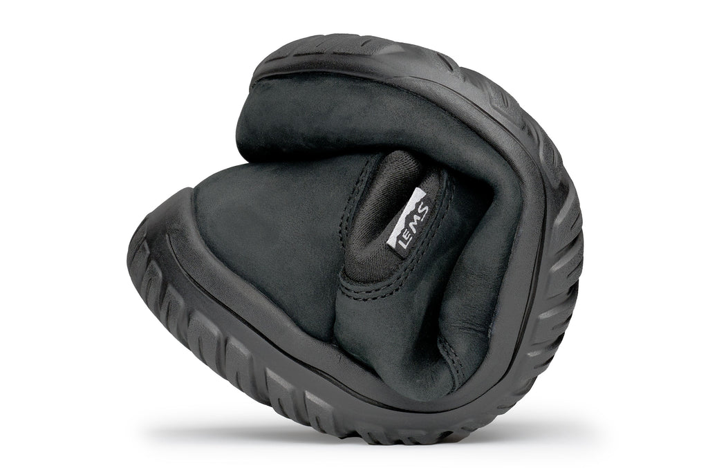 Black waterproof Chelsea boot folded to show flexibility and soft sole texture.