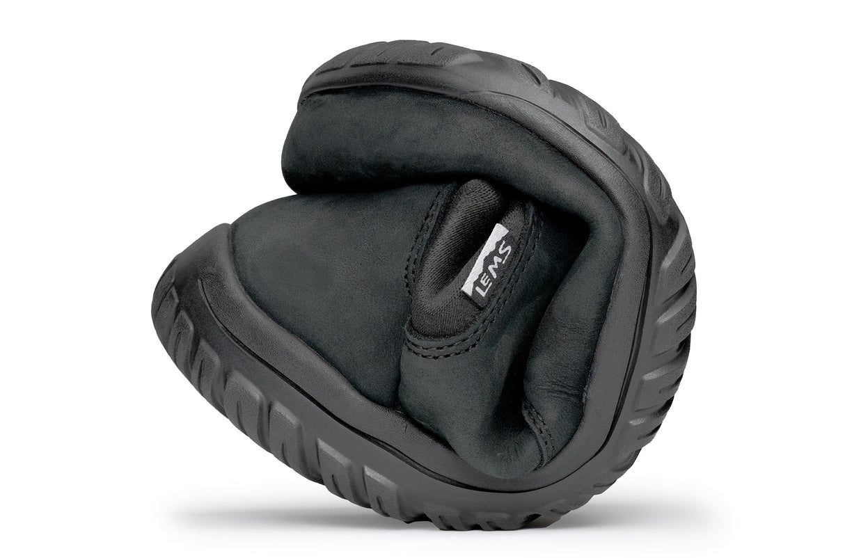Black waterproof Chelsea boot folded to show flexibility and soft sole texture.
