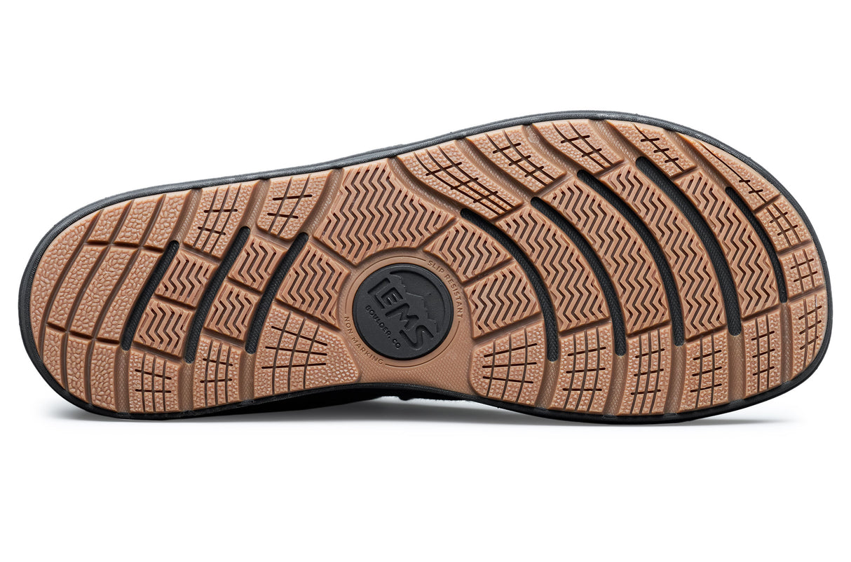 Black rubber outsole with deep tread pattern and central Lems logo on Lems Chukka Grip shoe.