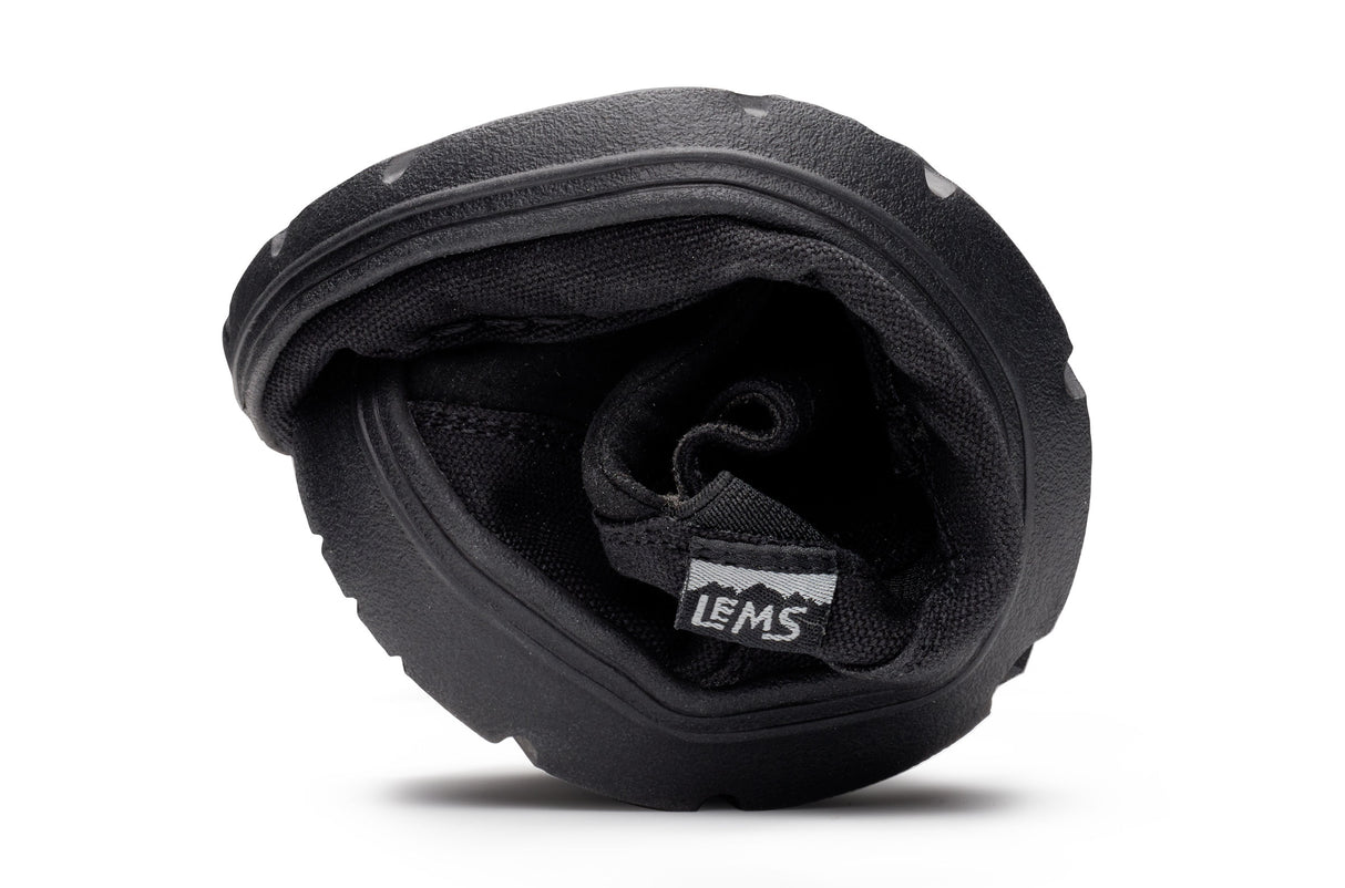 Black flexible Lems Drifter casual shoe folded to show its pliable sole and interior lining.