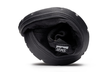 Black flexible Lems Drifter casual shoe folded to show its pliable sole and interior lining.