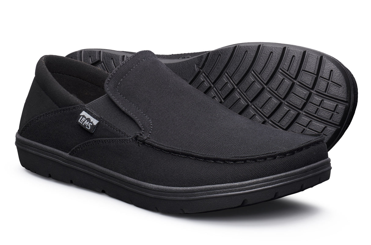 Black slip-on casual shoes with textured rubber sole and fabric upper, branded Lems tag on side.