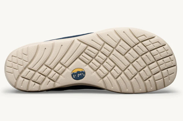 Beige rubber outsole with deep multi-directional grooves and small circular Lems logo in navy and yellow at the center.