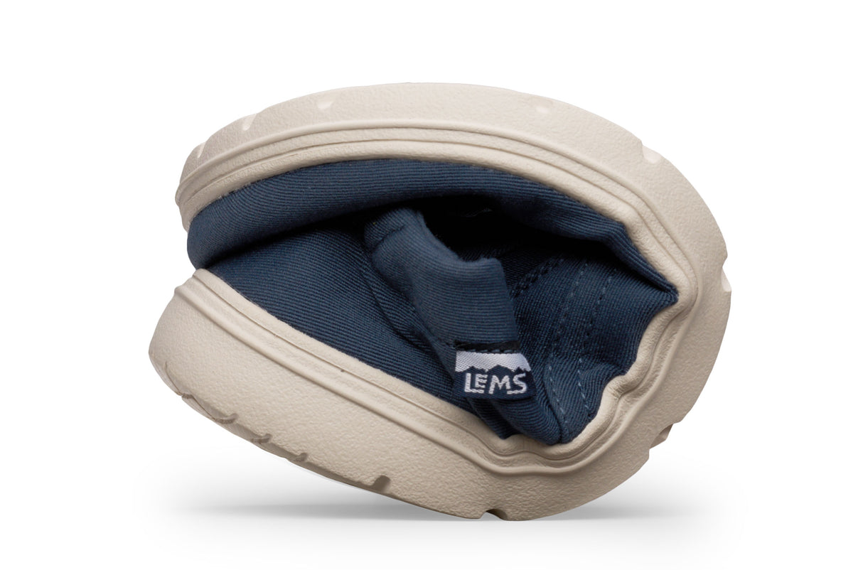 Flexible tan rubber sole fold showing navy blue fabric upper and Lems logo tag.