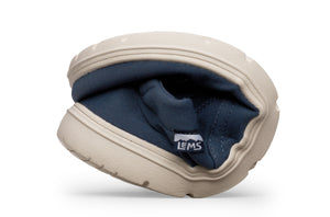 Flexible tan rubber sole fold showing navy blue fabric upper and Lems logo tag.