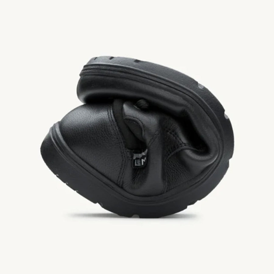 Flexible black leather casual shoe folded to show softness and outsole grip.