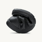 Flexible black leather casual shoe folded to show softness and outsole grip.