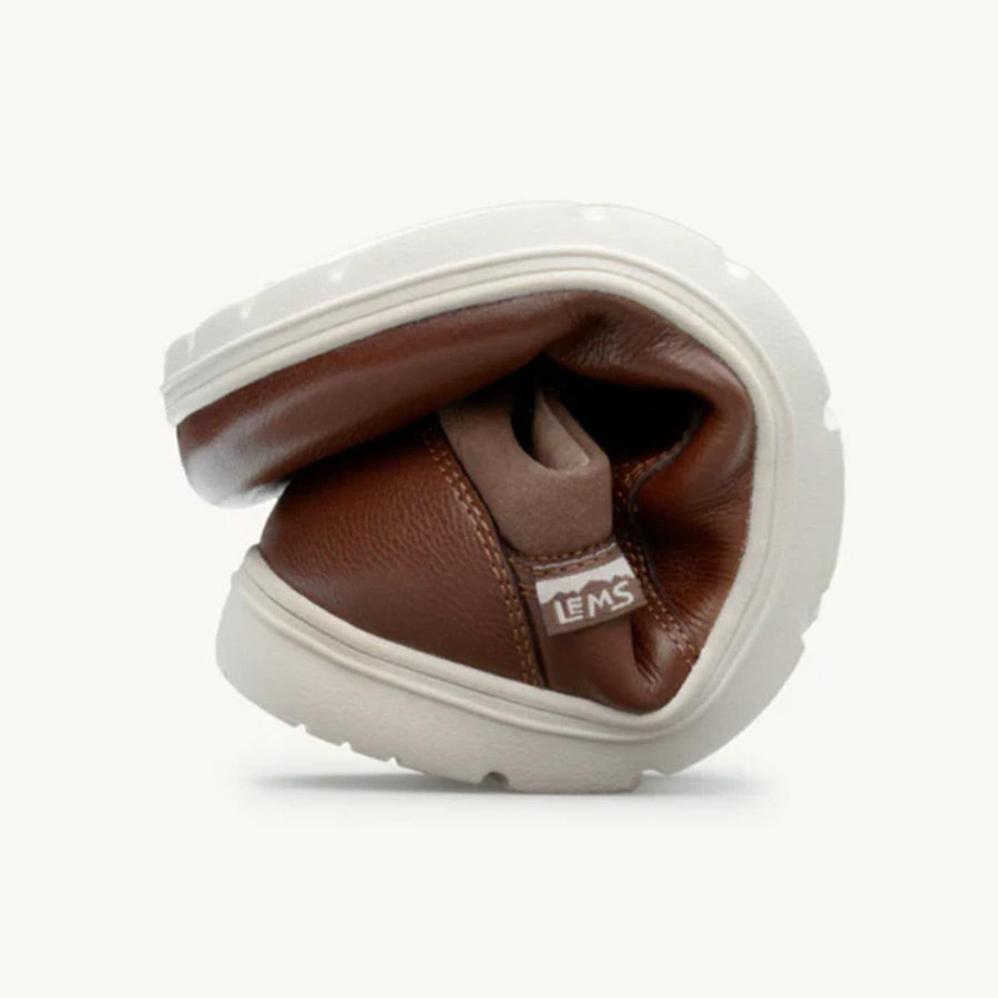 Flexible coffee brown leather casual shoe with cream rubber sole, bent to show flexibility.