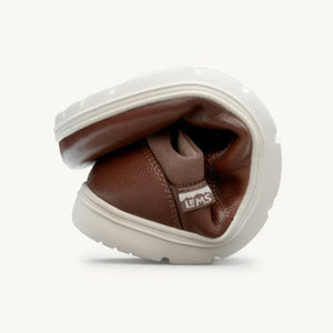 Flexible coffee brown leather casual shoe with cream rubber sole, bent to show flexibility.