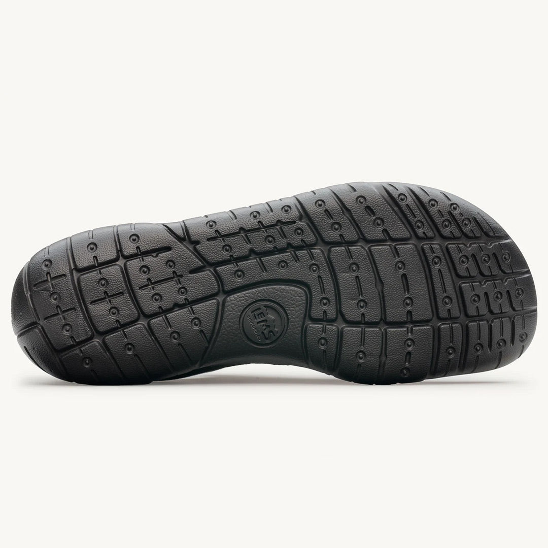 Black rubber sole with flexible grooves and circular traction patterns on the Lems Primal 3 shoe.
