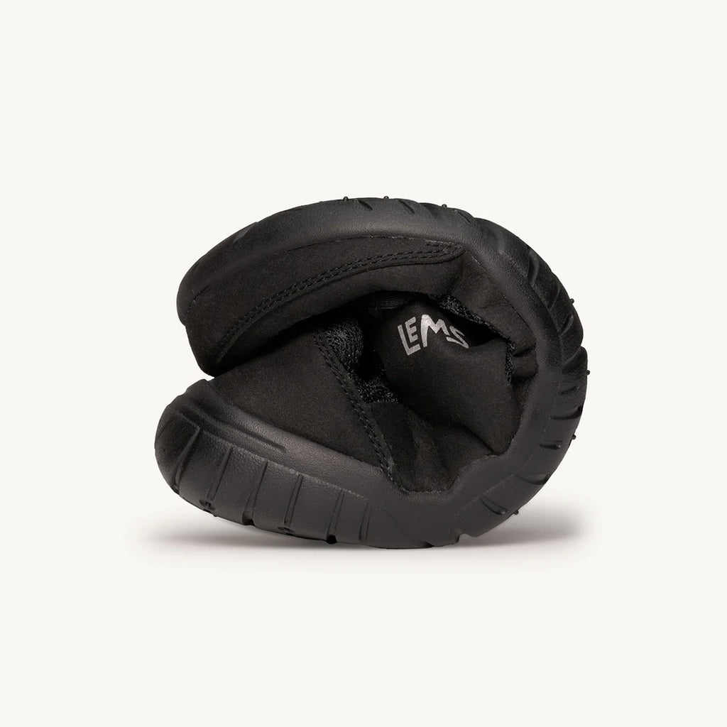 Black flexible athletic shoe tightly rolled to show softness and sole tread detail.