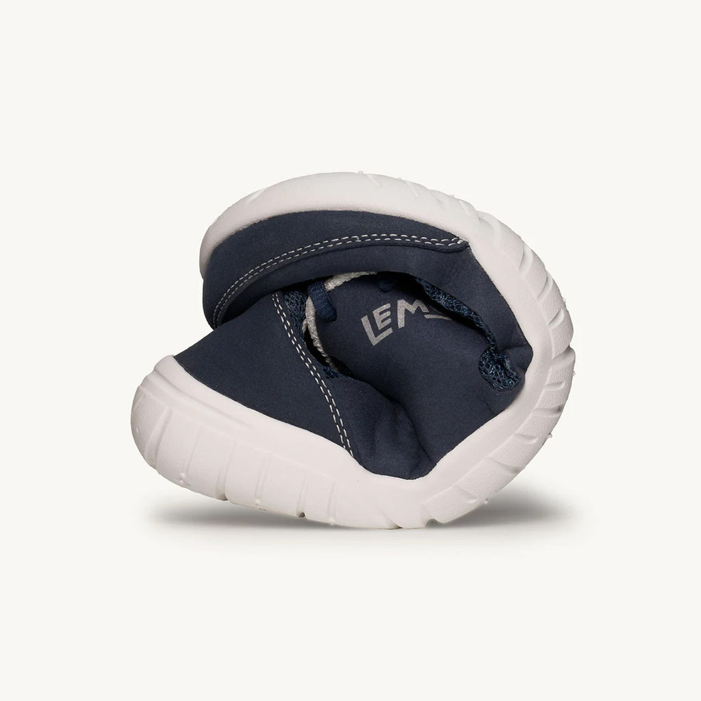 Navy blue Lems Primal 3 sneaker folded to show flexible white sole and soft upper material.