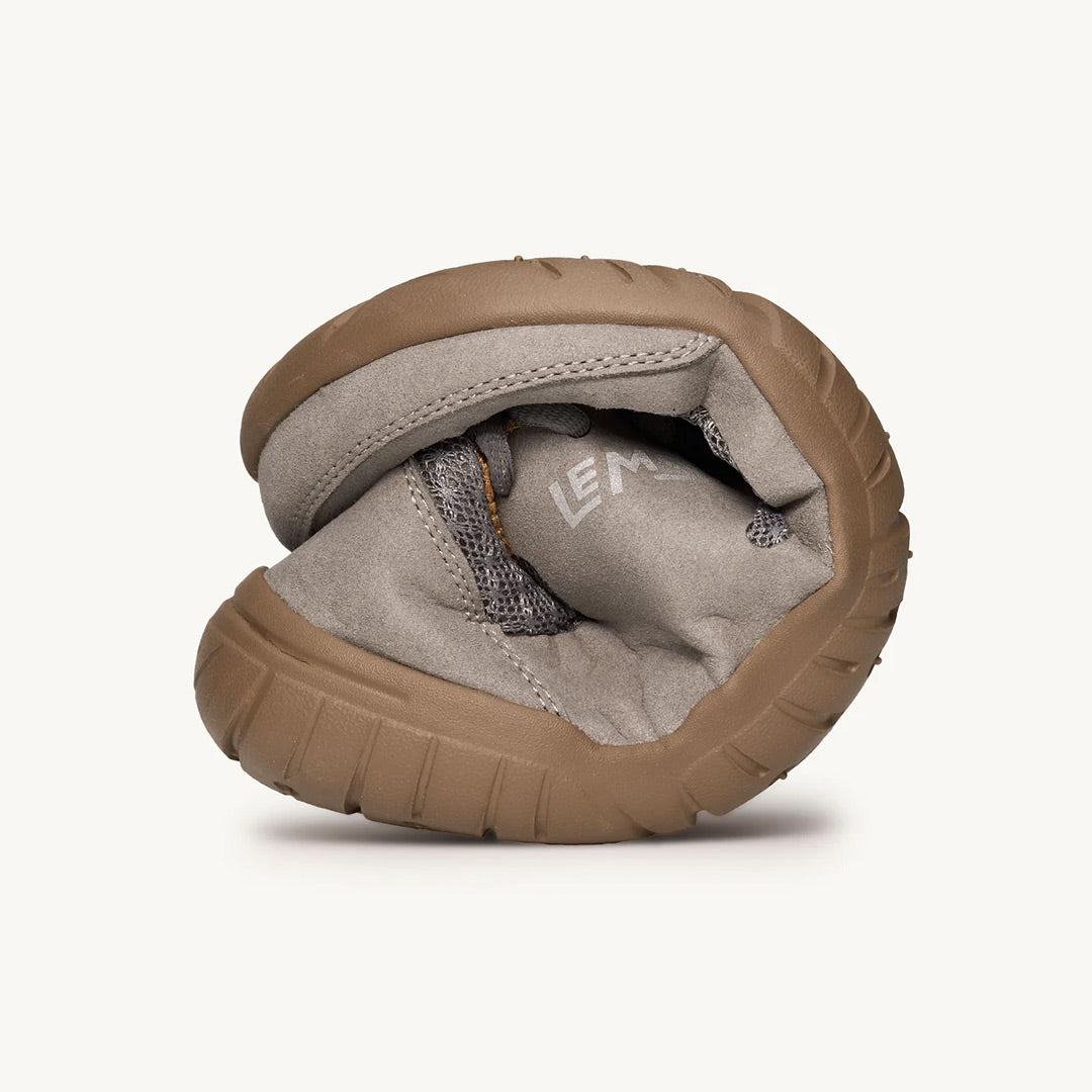 Flexible slate gray Lems Primal 3 sneaker bent to show foldability and brown rubber sole.