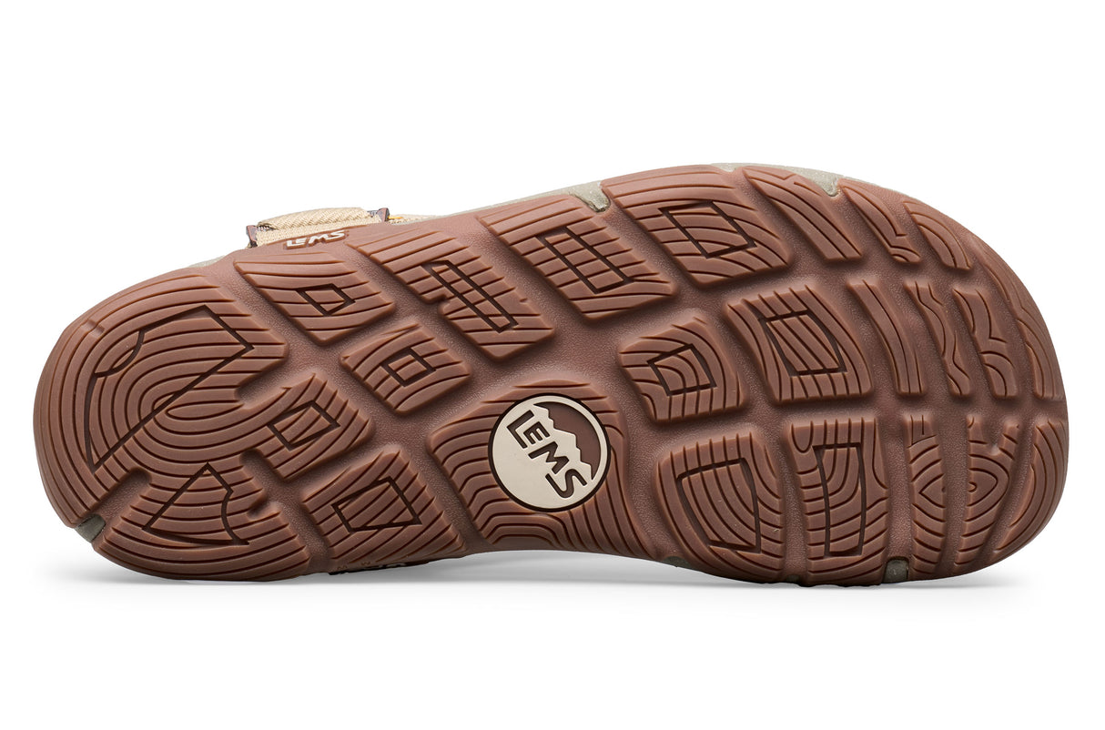 Brown rubber sole of Lems Switchback Mojave sandal with geometric tread pattern and logo embossed in center.