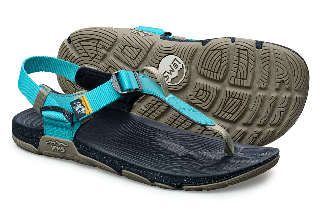Teal and black minimalist athletic sandals with adjustable straps and textured rubber soles.