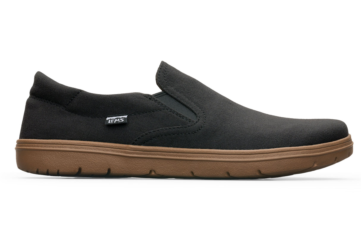Black slip-on casual shoe with brown rubber sole and a small side Lems logo tag.