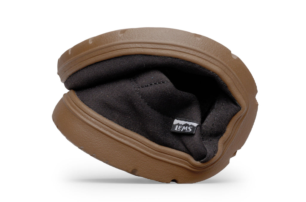 Flexible black slip-on shoe with brown sole folded in half showing bendability.