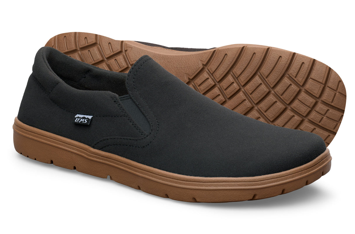 Black slip-on casual shoes with elastic side panels and brown textured rubber soles.
