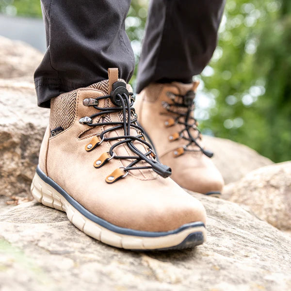 Tan leather boots with black no-tie Lock Laces and rugged soles on rocky terrain.