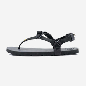 Black minimalist sandal with thin straps and adjustable buckles on flat sole.