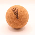 A round cork massage ball with a dark brown printed skeletal foot design, shown on a clean white background.