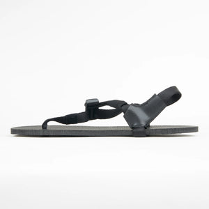 Black minimalist sandal with thin adjustable straps and flat sole shown in side profile.
