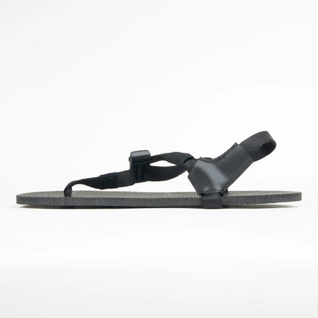 Black minimalist sandal with thin adjustable straps and flat sole shown in side profile.