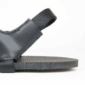 Black textured flat sandal with wide heel strap and cushioned footbed.