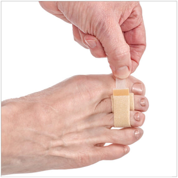 Narrow beige fabric toe loop wrapped around a big toe on a bare foot.